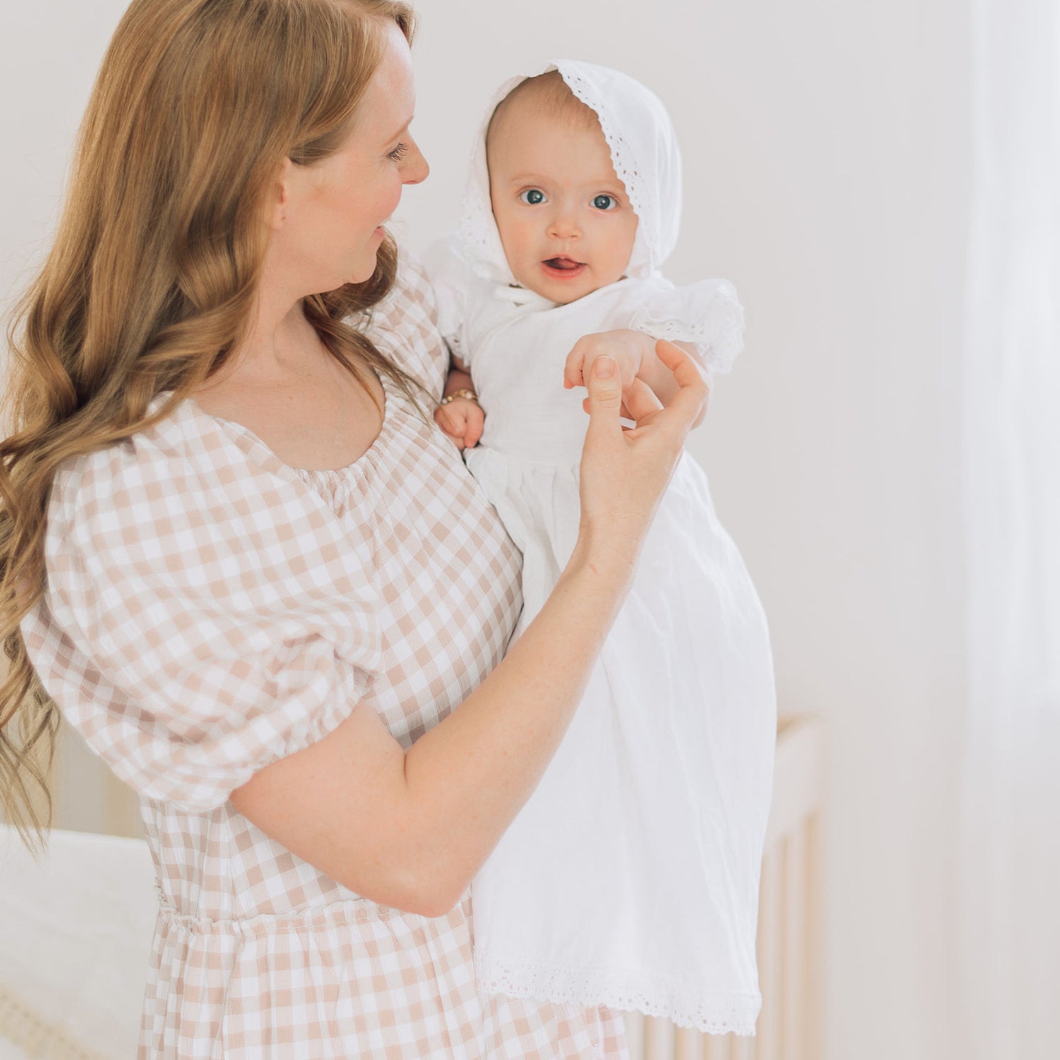 Mom holding babies hand in blessing outfit
