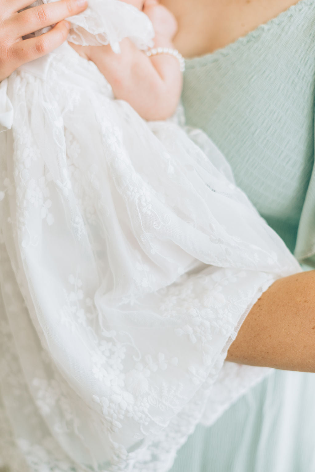 Detail shot of baby girls white lace dress.