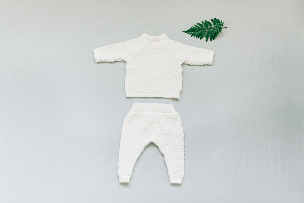 Back view of long sleeve and long pants white baby boy blessing outfit set on flat lay.