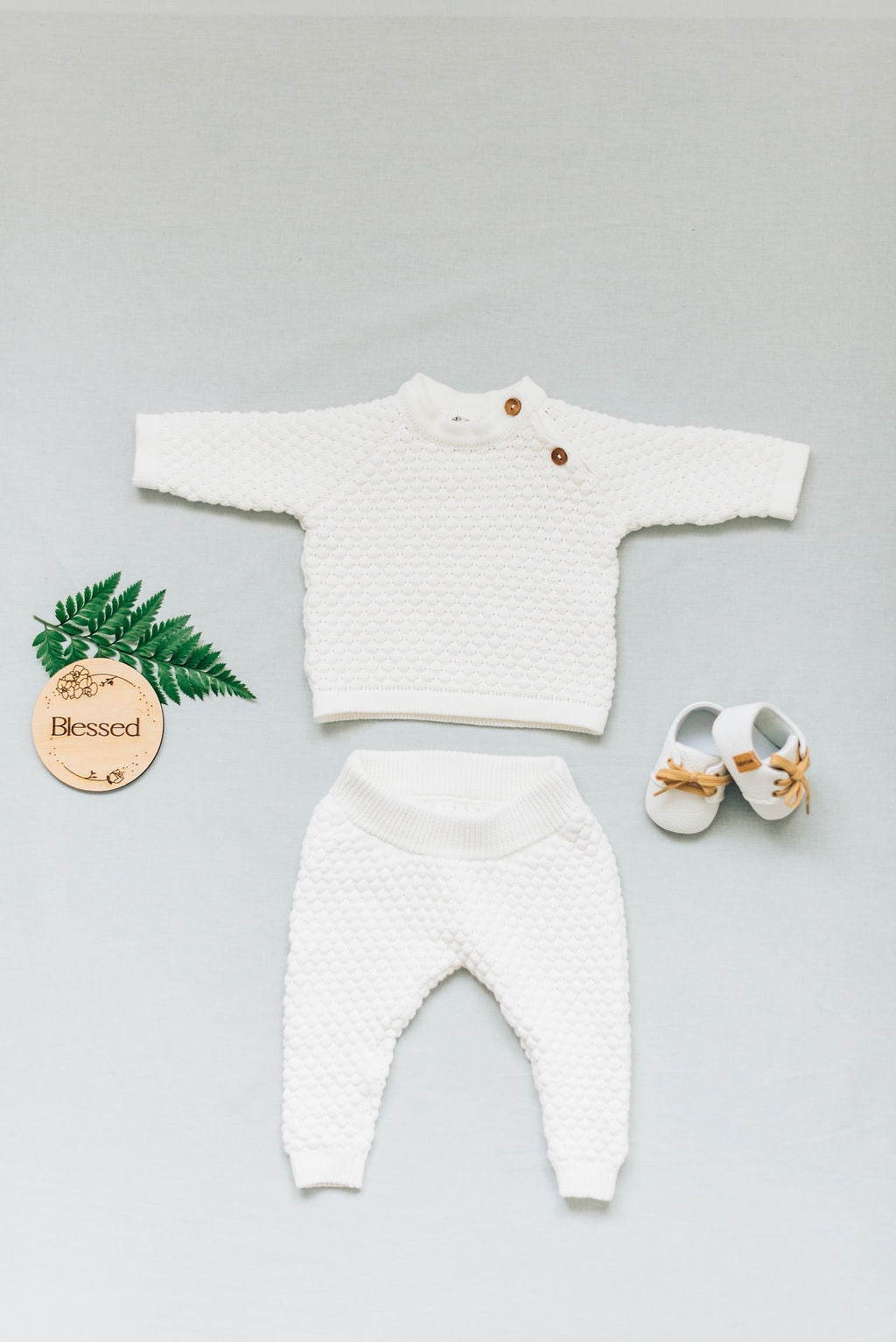 Flat lay of white baby boy set, long sleeves and long pants.