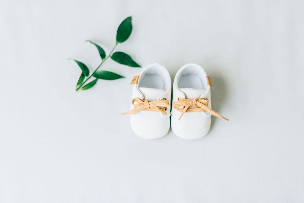 Front view of white baby shoes with laces.