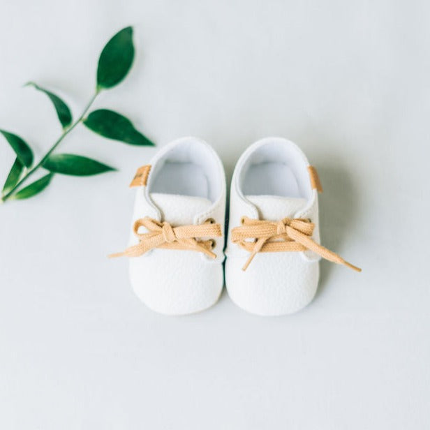 Front view of white baby shoes with laces.