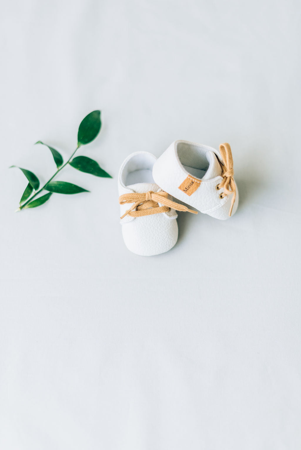 White baby boy shoes with brown laces.