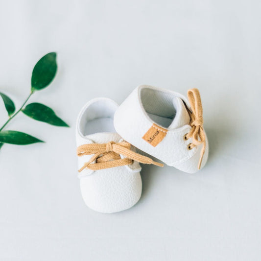 White baby boy shoes with brown laces.