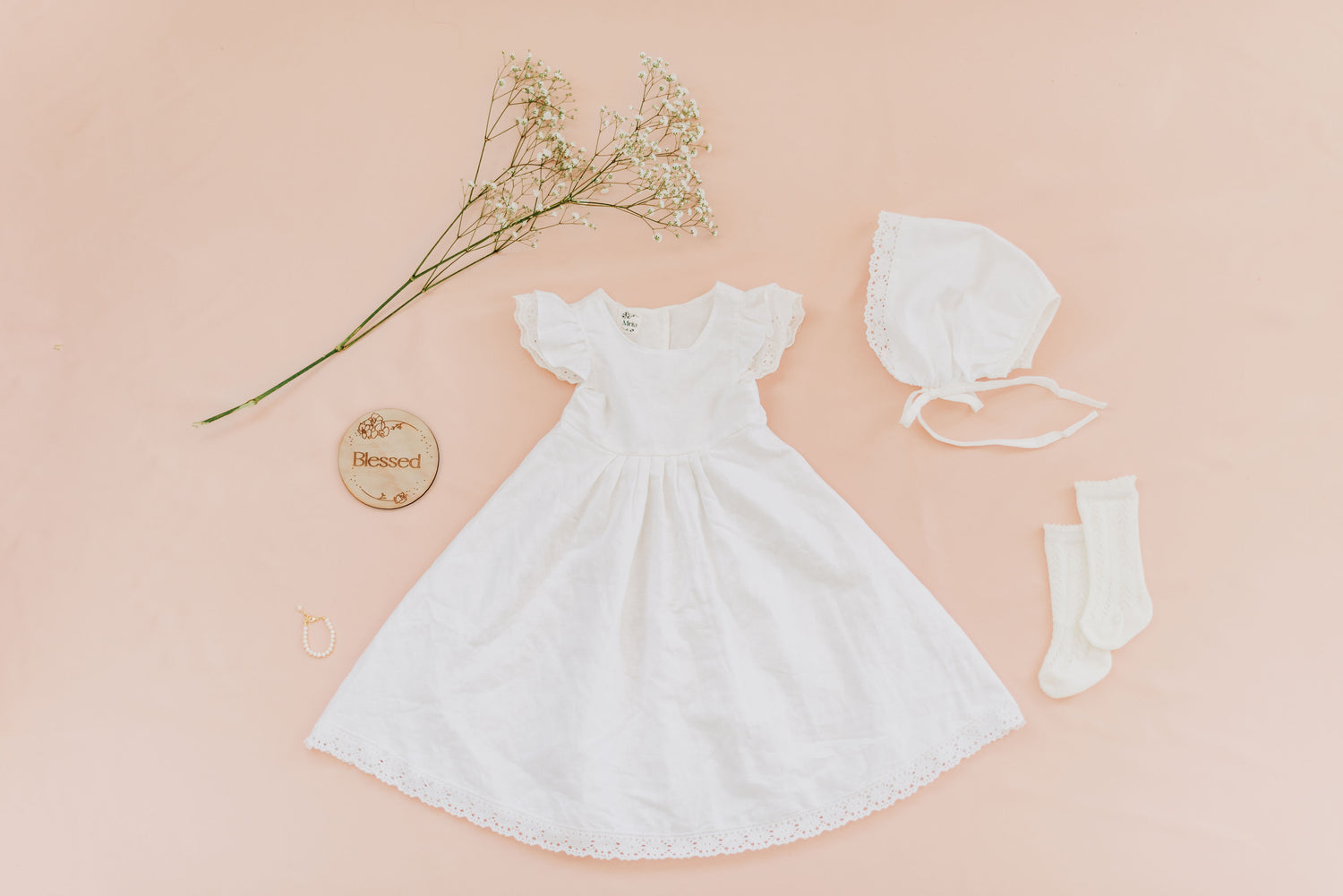 Flat lay with baby girl blessing dress, knit socks, and bonnet.