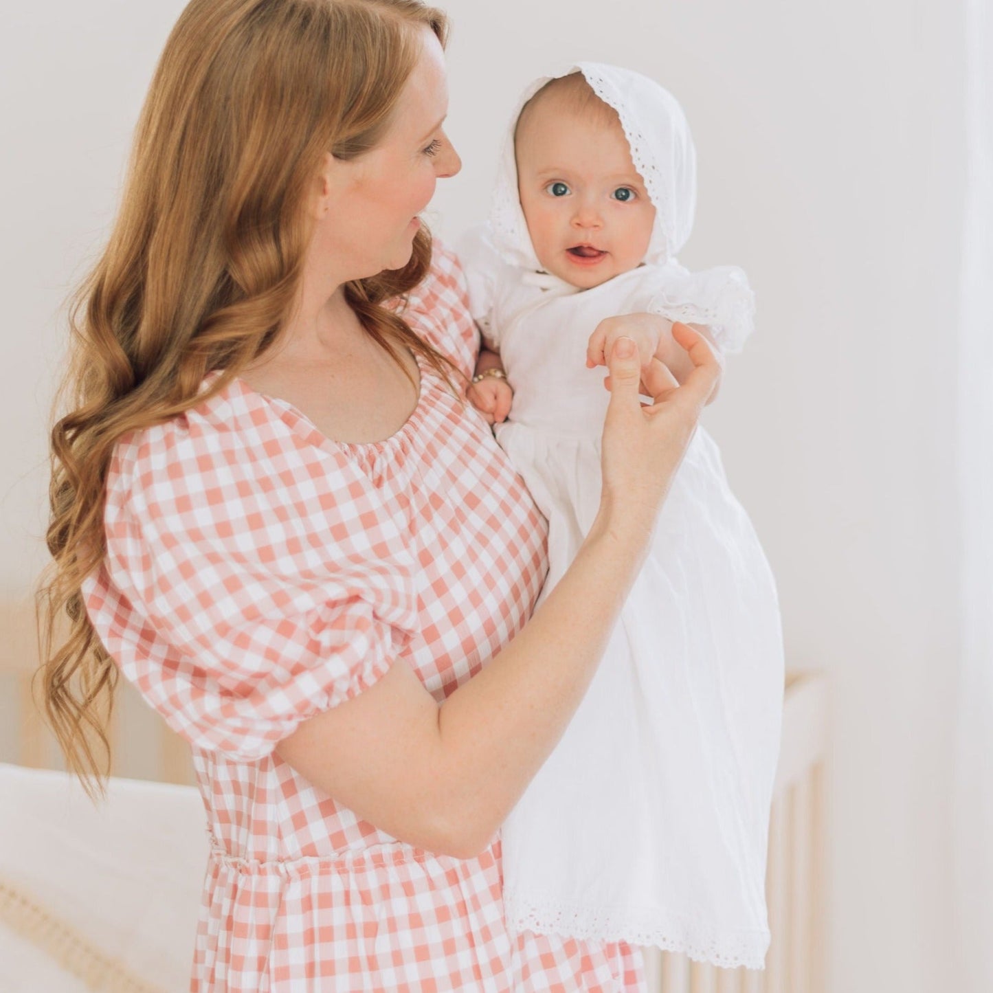 Mom holding babies hand in blessing outfit